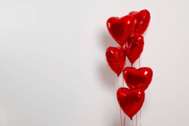 Beyaz arkaplanda birçok kırmızı kalp şekilli balon, metin için boşluk