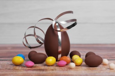 Lezzetli çikolata yumurtaları ve ahşap masada renkli şekerler.