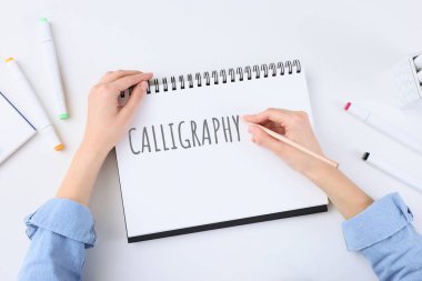 Beyaz masadaki deftere yazı yazan kadın, üst görünüm