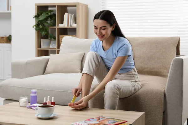 stock image Beautiful young woman giving herself pedicure in living room