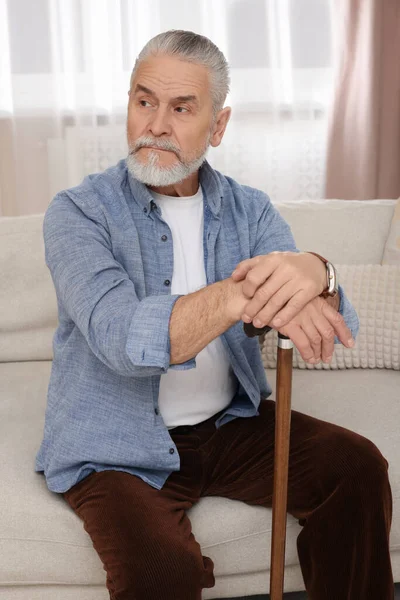 老年人 拿着手杖坐在家里的沙发上 — 图库照片