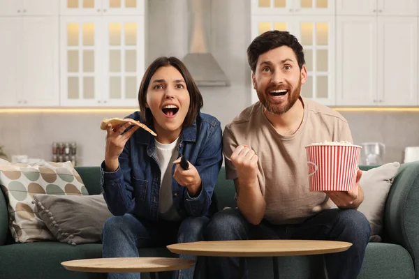 Překvapený Pár Sledující Televizi Popcornem Pizzou Doma Gauči — Stock fotografie