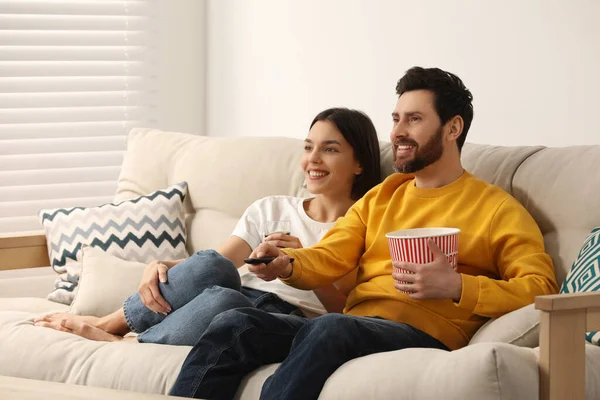 快乐的夫妻在家里的沙发上看电视 吃爆米花 — 图库照片