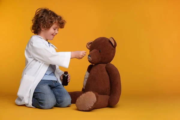 Mały Chłopiec Bawiący Się Doktora Niedźwiedziem Żółtym Tle Miejsce Tekst — Zdjęcie stockowe