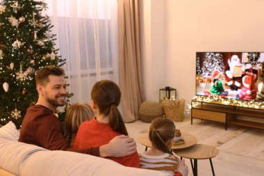 Mutlu aile TV 'nin yanında, rahat bir odada birlikte vakit geçiriyor. Noel atmosferi