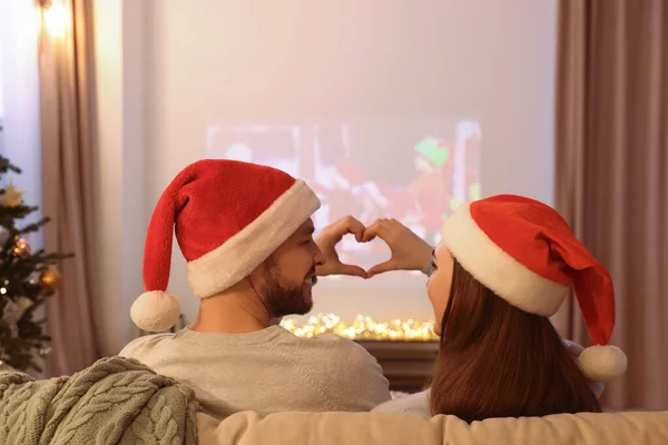 部屋のビデオプロジェクターの近くに手で心を作るカップル クリスマスの雰囲気 — ストック写真