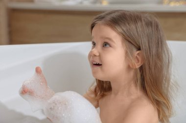 Şirin küçük kız evde köpüklü banyo yapıyor. Saç yıkama.