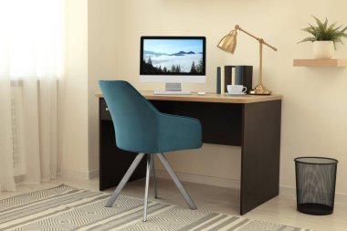 Samimi çalışma alanı, ahşap masa üzerinde bilgisayar ve evdeki rahat sandalye.