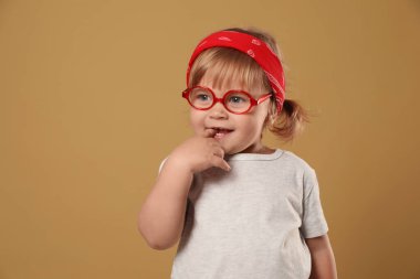 Soluk kahverengi arka planda gözlüklü şirin bir kız. Metin için boşluk