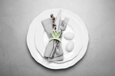 Renkli yumurtalar ve açık gri arka planda söğüt dallı şenlik masası, üst manzara. Paskalya kutlaması