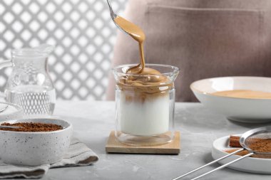 Açık gri masada dalgona kahvesi yapan kadın, yakın plan.