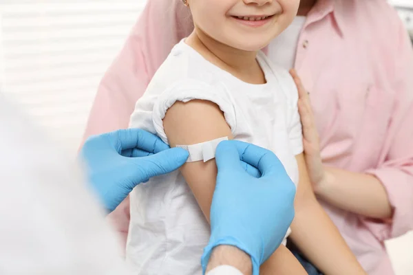 儿童肝炎疫苗接种 妈妈带着女儿在诊所里医生把药膏贴在小女孩的胳膊上 — 图库照片