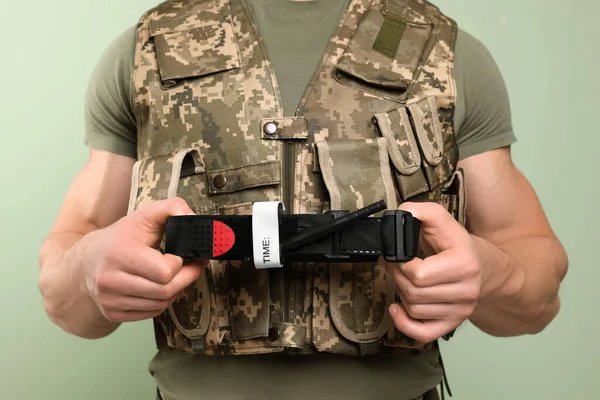 Żołnierz Mundurze Wojskowym Trzymający Opaskę Uciskową Jasnym Tle Oliwki Zbliżenie — Zdjęcie stockowe