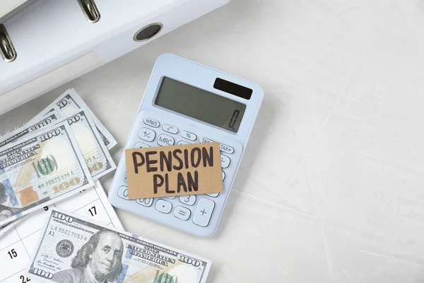 Card with phrase Pension Plan, dollar banknotes and calculator on white office table, flat lay. Space for text
