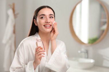 Güzel bir kadın içeride pamukla makyajı temizliyor.