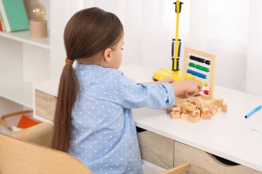 Masadaki tahta küplerle oynayan tatlı küçük kız. Ev işyeri