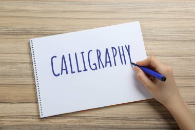 Ahşap masadaki deftere yazı yazan kadın, üst görünüm