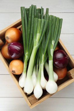 Beyaz ahşap masa üzerinde farklı türde soğan olan sandık.
