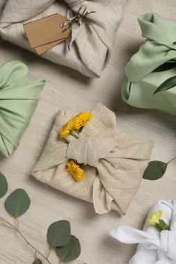 Furoshiki tekniği. Kumaş, çiçek ve okaliptüs yaprakları içinde bir sürü hediye.