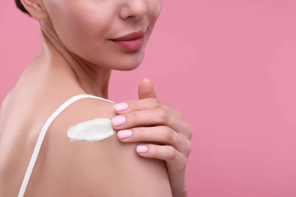 stock image Woman with smear of body cream on her shoulder against pink background, closeup. Space for text