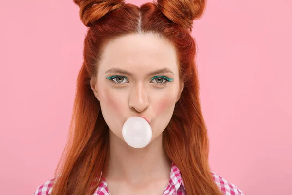 stock image Portrait of beautiful woman with bright makeup blowing bubble gum on pink background