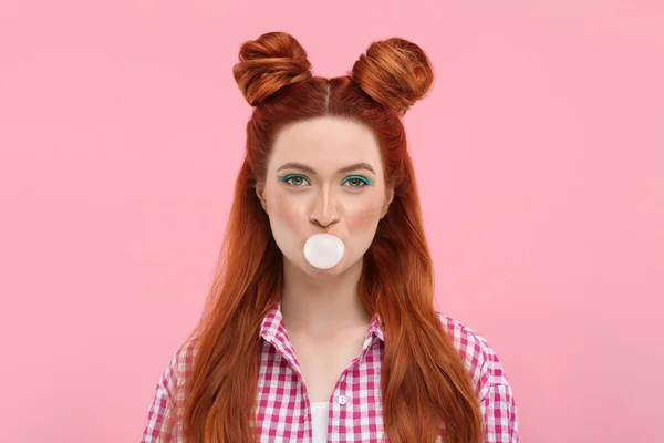 stock image Portrait of beautiful woman with bright makeup blowing bubble gum on pink background