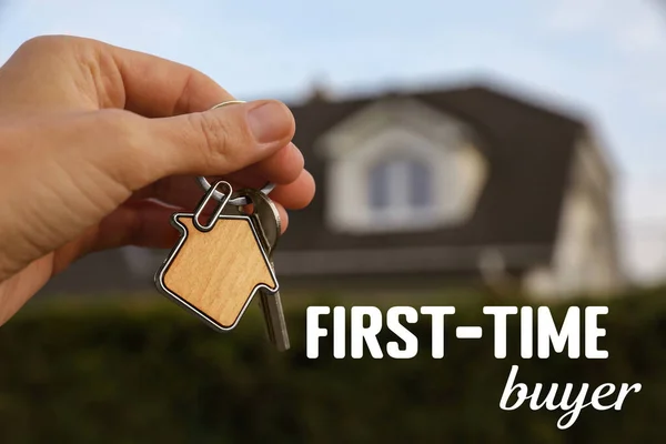 First-time buyer. Woman holding house keys outdoors, closeup