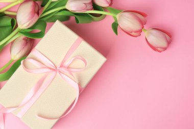 Pembe arka planda fiyonklu ve laleli güzel bir hediye kutusu var. Metin için boşluk