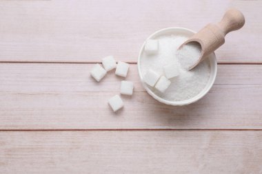 Rafine edilmiş ve granüllenmiş beyaz şeker. Tahta masada, düz yerde. Metin için boşluk