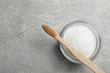 Bambu diş fırçası ve gri masada bir kase kabartma tozu, üst manzara. Metin için boşluk