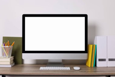 Modern bilgisayar ve ahşap masadaki kırtasiye malzemesi ile rahat çalışma alanı