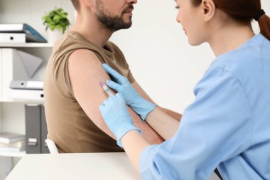 Doktor klinikteki hastaya hepatit aşısı veriyor.