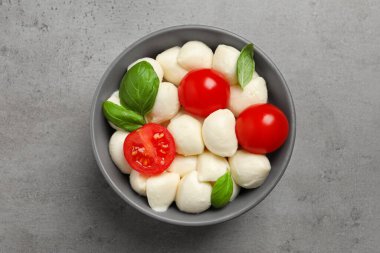 Nefis mozzarella topları, domatesler ve fesleğen yaprakları açık gri masa, üst manzara