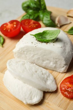 Ahşap tahtada domates ve fesleğen yapraklı lezzetli mozzarella, yakın plan.