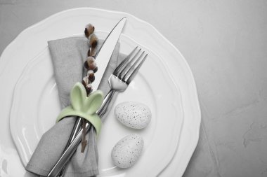 Renkli yumurtalar ve açık gri arka planda söğüt dallı şenlik masası, üst manzara. Paskalya kutlaması