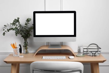 Samimi çalışma alanı bilgisayar, kulaklık ve ahşap masadaki kırtasiye malzemeleriyle.