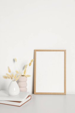Boş fotoğraf çerçevesi ve beyaz masa üzerinde kuru dekoratif çiviler olan vazolar. Tasarım için model
