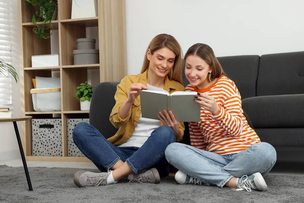 快乐的母亲和她十几岁的女儿在家里的地板上看书 — 图库照片