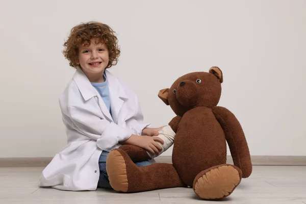 Kleiner Junge Arztuniform Und Spielzeugbär Mit Verband Drinnen — Stockfoto