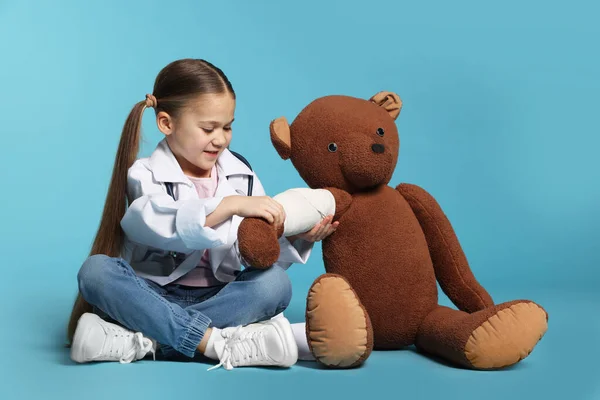 Маленькая Девочка Медицинской Форме Игрушечный Медведь Повязкой Светло Голубом Фоне — стоковое фото