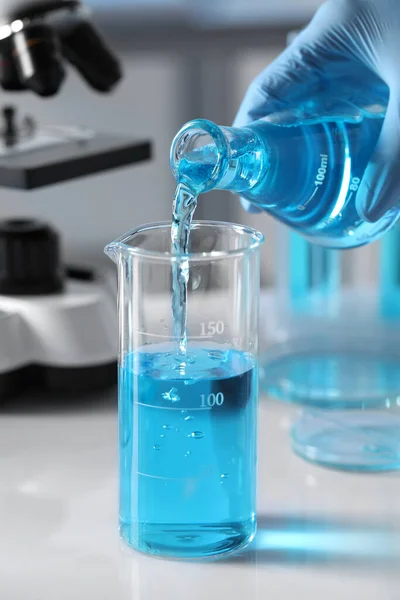 Ученый Наливает Светло Голубую Жидкость Колбы Стакан Лаборатории Крупным Планом — стоковое фото
