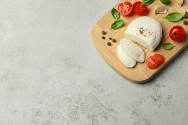 Açık gri masa üzerinde domates ve fesleğen yapraklı lezzetli mozzarella. Metin için boşluk