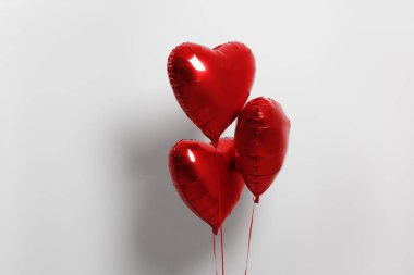 Many red heart shaped balloons on white background
