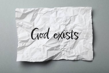 Metni olan buruşuk kağıt. Tanrı gri arkaplanda var. Üst görünümde.