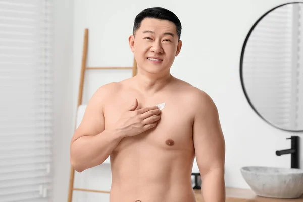 Yakışıklı Adam Banyoda Göğsüne Vücut Kremi Sürüyor — Stok fotoğraf