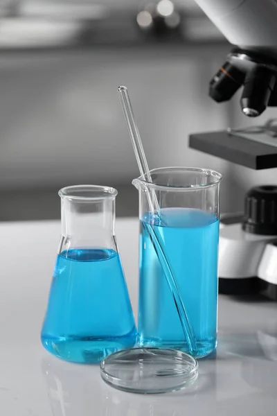 Olika Laboratorieglas Med Ljusblå Vätska Nära Mikroskop Bordet — Stockfoto