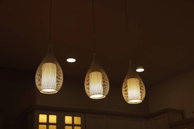 Ceiling with modern lamps and furniture in stylish kitchen at night, low angle view