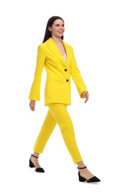 Sarı takım elbiseli güzel bir iş kadını beyaz arka planda yürüyor.