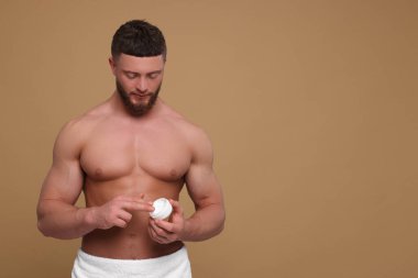 Soluk kahverengi arkaplana vücut kremi süren yakışıklı adam, metin için boşluk