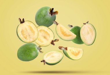 Soluk sarı arka planda taze feijoa meyveleri düşüyor